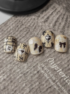 Detail of 3D embossed black bows and pearl heart elements on handmade press-on nails