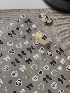 Macro detail of 3D embossed nail stickers with gold bow and heart patterns