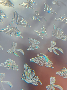 Macro view of 3D embossed butterfly nail stickers with iridescent shell aurora effect