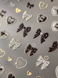 Macro shot of 3D embossed nail art stickers with bows and golden heart textures