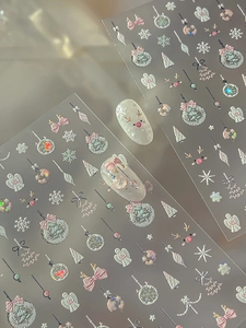 Macro shot of 3D Christmas nail stickers with pink bows, reindeer and embossed textures