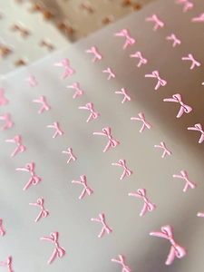 Vue macro de stickers ongles nœud rose en relief 3D avec détails texturés délicats