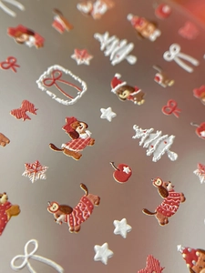 Detailed macro view of 3D embossed Christmas dog nail art stickers with sweater patterns