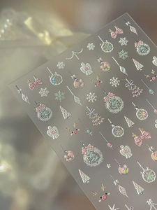 Detailed macro of 3D embossed Christmas nail stickers featuring silver snowflakes and trees