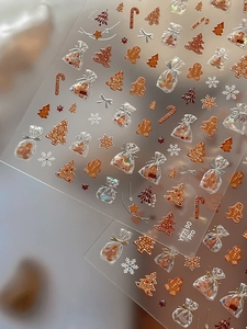 Macro view of gingerbread man and gold snowflake nail art stickers with embossed texture
