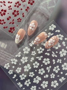 Detail of 3D embossed white and red flower nail stickers on almond nails with glitter finish