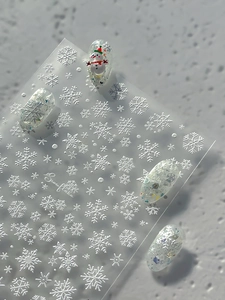 Macro view of embossed white snowflake nail stickers and Christmas snowman nail art details