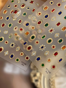 Dettaglio macro di adesivi per unghie 3D stile vittoriano con goffratura dorata e gemme