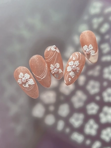 Detailed view of 3D embossed white flowers and pearls on nude glitter nail stickers