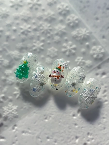 Detailed view of Christmas nail charms featuring 3D trees, snowmen, and glittery snowflakes