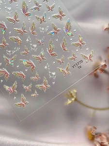 Close-up of holographic butterfly nail art stickers with aurora glitter and heart details