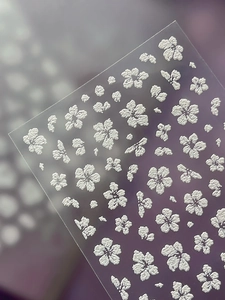 Detailed macro view of 3D embossed floral nail stickers with white textured petal designs