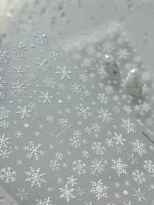 Close-up of 3D embossed white snowflake nail art stickers with frosted matte texture