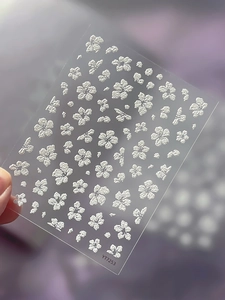 Detailed macro view of white embossed 3D floral nail art stickers on a clear sheet