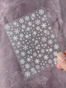 Detail of white 3D snowflake embossed nail art stickers on transparent film backing