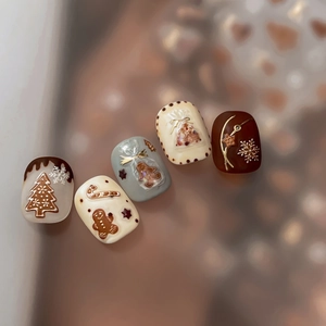 Golden Christmas press-on nails featuring 3D embossed gingerbread man and tree designs