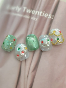Detail of mint green and pearl white press-on nails with 3D beads and gold chain charms