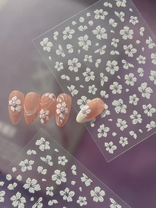 Detail of 3D embossed white flower nail art stickers with relief texture on pink nails