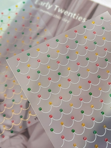 Detailed close-up of wavy gold nail stickers with colorful rhinestones and gold stars