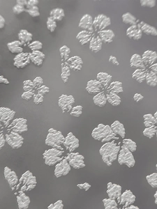 Macro shot of silver embossed floral nail stickers with 3D texture and metallic finish