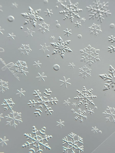 Detailed macro view of 3D embossed white snowflake nail stickers for winter nail art