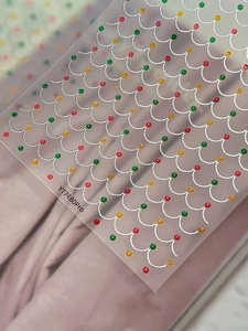 Macro detail of Christmas nail stickers with red, green, and gold geometric star patterns