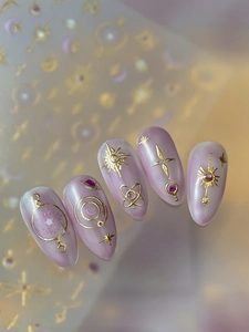 Detail of purple pearlescent nails with embossed golden sun star and moon patterns