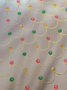 Macro shot of festive gold chain nail stickers with red and green sequins on grey surface