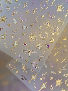 Macro detail of gold foil celestial nail stickers with sun moon and stars patterns
