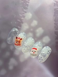 Dettaglio degli adesivi per unghie 3D Babbo Natale e renna su unghie viola con fiocchi