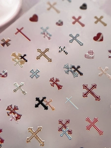 Macro detail of gothic cross and red heart patterns on professional nail art stickers