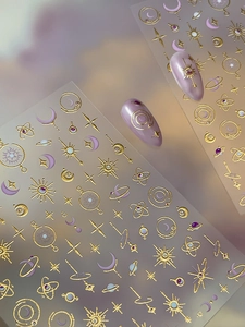 Detail of gold moon and star nail stickers with purple cosmic galaxy celestial patterns