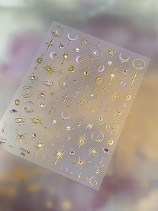 Detail of gold foil celestial moon and star nail stickers with purple galaxy design