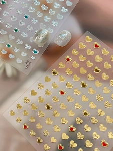 Detailed macro view of gold and silver heart-shaped nail art stickers with embossed patterns