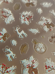 Makro-Detail von 3D-Relief-Weihnachtsnagelstickern mit Rentieren und Stechpalmenbeeren