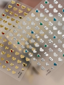 Macro detail of 3D embossed heart nail stickers with metallic gold and silver finish