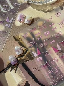 Macro detail of 3D embossed pink and purple bow nail stickers with chain textures
