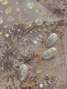 Detail of vintage gold embossed shell and star moon nail art stickers on a display card