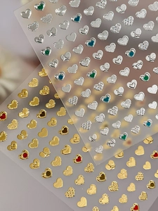 Macro detail of 3D embossed heart nail stickers with gold and silver metallic textures