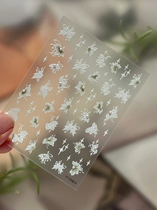 Macro detail of 5D embossed nail art stickers with white flowers and faux pearls