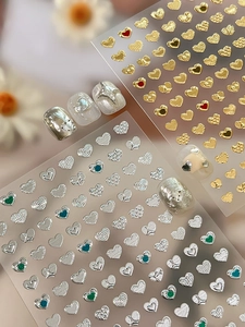 Macro detail of gold and silver heart nail stickers with embossed metallic textures