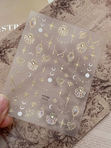 Macro detail of YT7099 Pro S gold foil nail stickers with shell and star designs