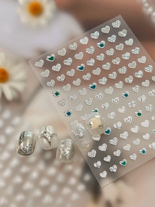 Detailed macro view of 3D embossed silver heart nail stickers with metallic chrome textures
