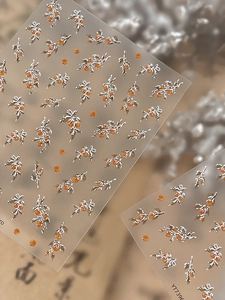 Detailed view of 3D embossed nail art stickers with silver branches and orange berries