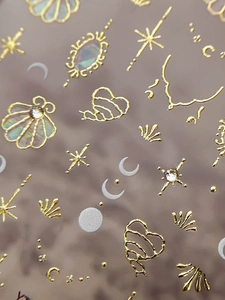 Macro detail of gold embossed nail stickers with shell and star patterns and rhinestones