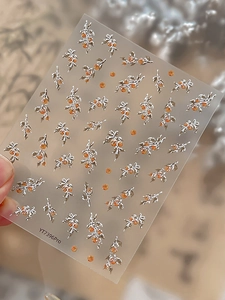 Detailed close-up of 3D embossed silver holly branches and orange berry nail art stickers