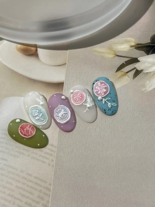 Macro detail of 3D embossed nail art stickers with floral and love letter wax seal motifs