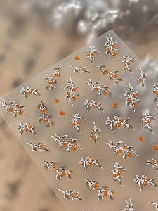 Macro shot of 3D embossed orange berries and snowy branches on nail art stickers