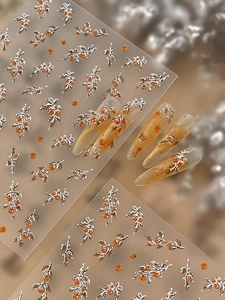 Macro detail of 3D embossed nail stickers featuring silver branches and orange persimmons