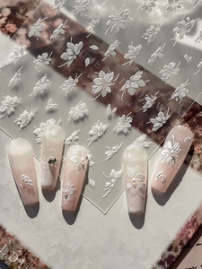 Détail d'autocollants 3D gaufrés fleurs et papillons blancs sur ongles dégradés
